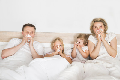 Sick Family Lying In Bed At Home